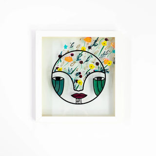 Framed artwork of a stylized face with floral patterns on a white background